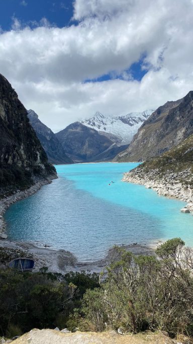 Lac turquoise entouré de montagnes et de nuages, dans un paysage naturel spectaculaire.