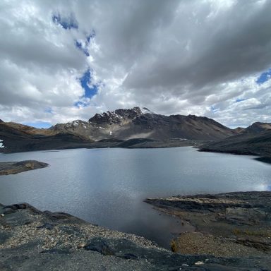 Lac paisible entouré de montagnes sous un ciel nuageux.