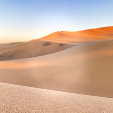 Dunes de sable doré sous un ciel clair au crépuscule.