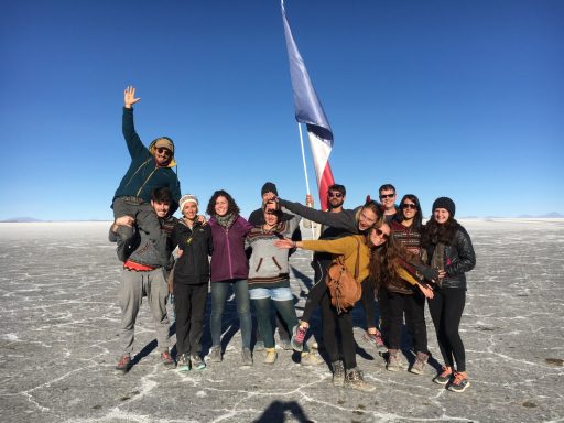 Groupe de personnes souriantes posant sur une surface saline sous un ciel dégagé.